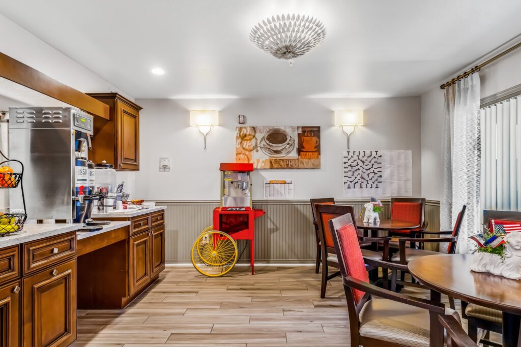 MG_4482 - The Ranch Estates at Scottsdale A dining area with brown tables and red-cushioned chairs, brown cupboards, fruit baskets, water pitcher, and a popcorn machine at The Ranch Estates at Scottsdale.